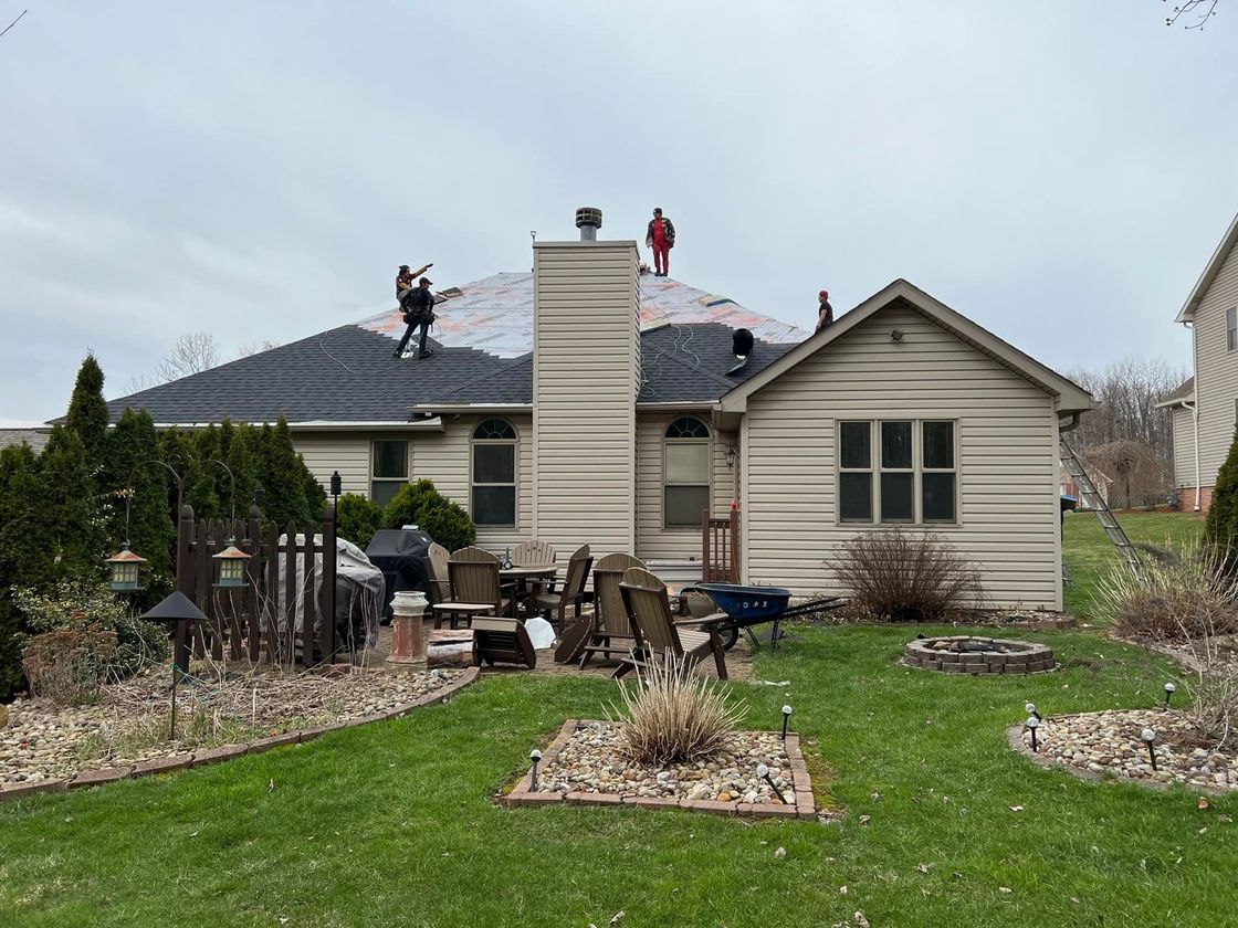 A group of people are working on the roof of a house.