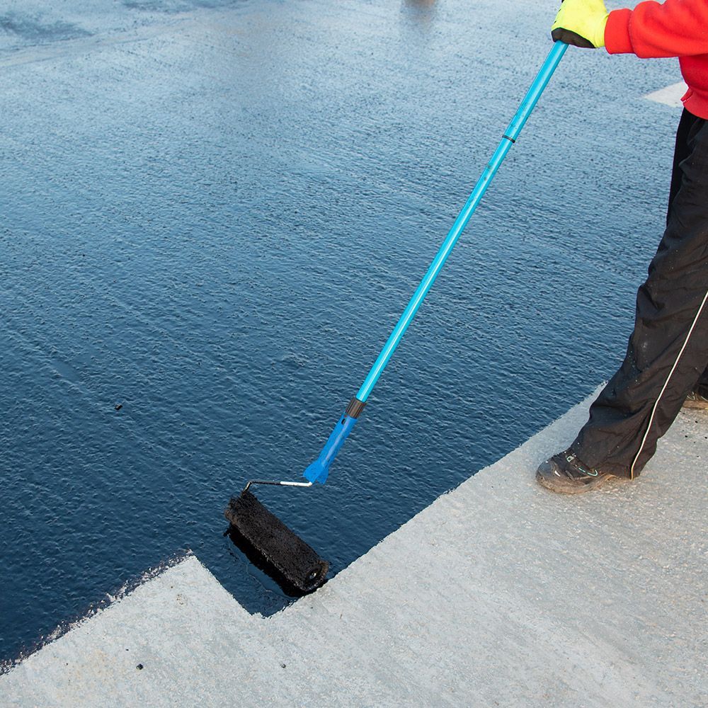 A person is painting a concrete surface with a roller