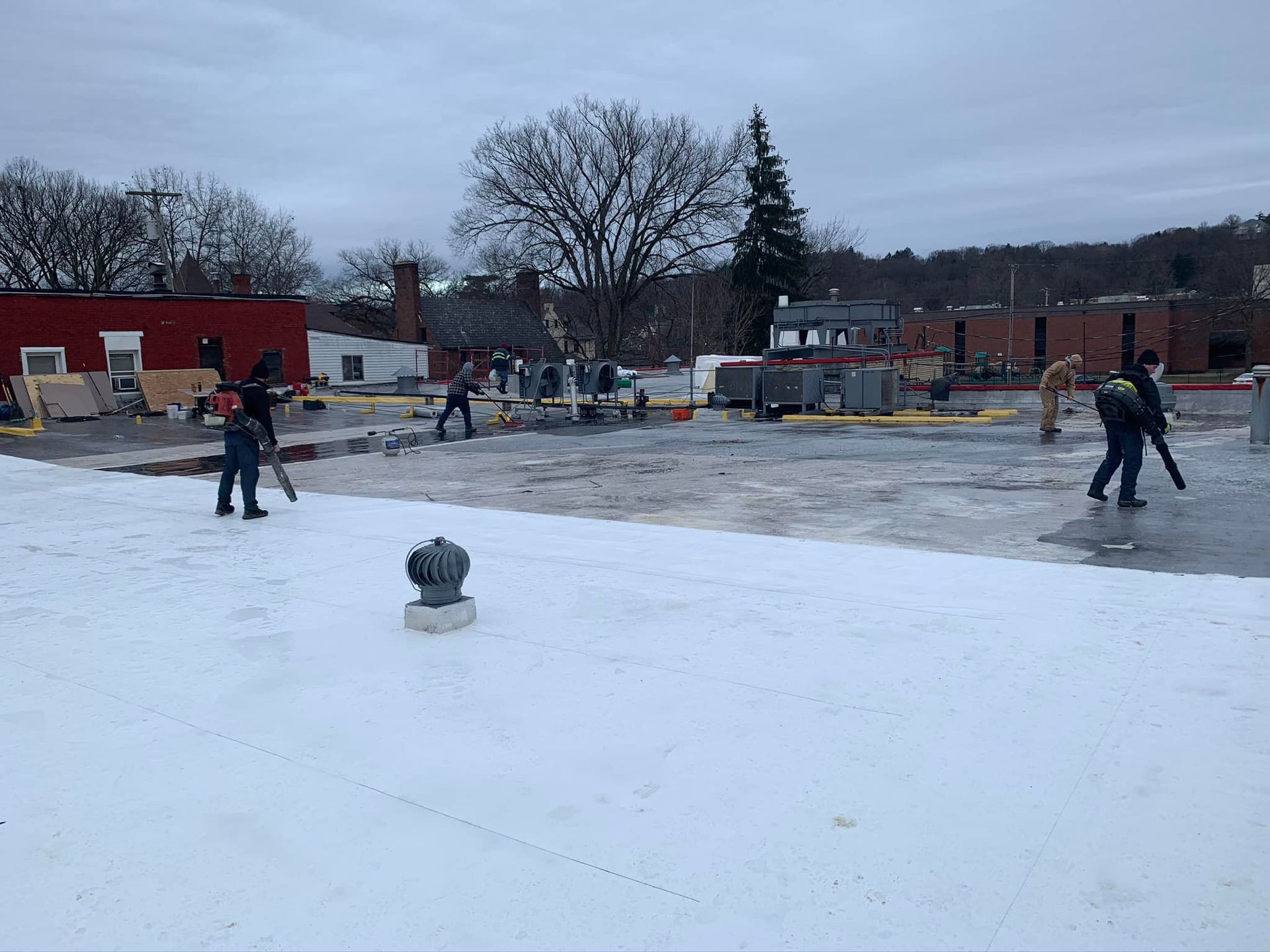 A group of people are working on a snowy roof.
