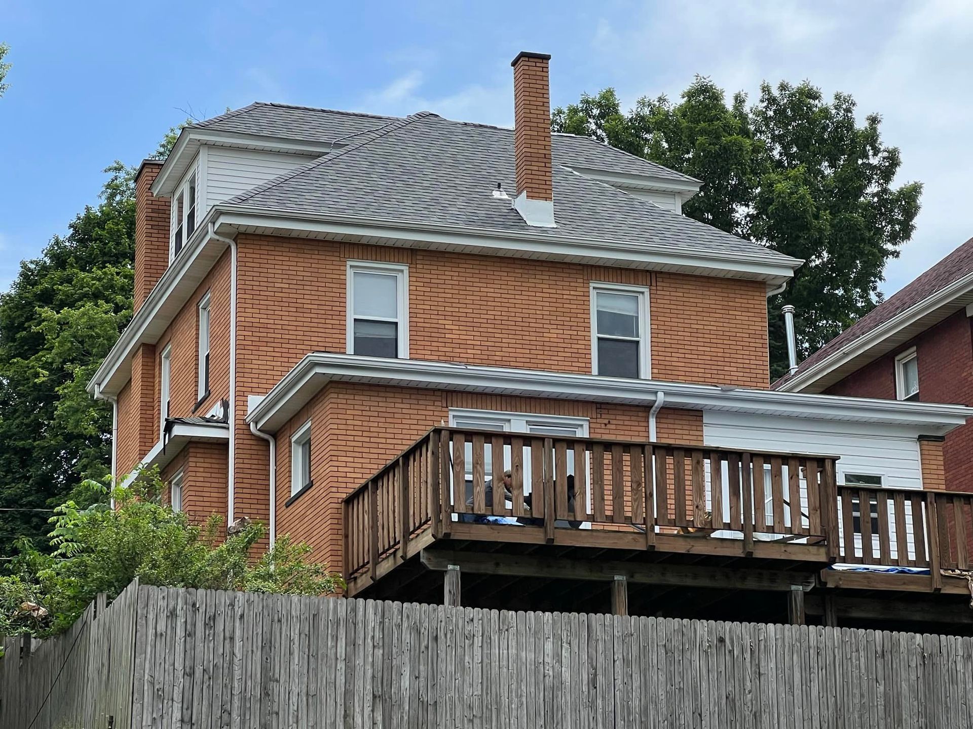 A large brick house with a wooden deck and a chimney