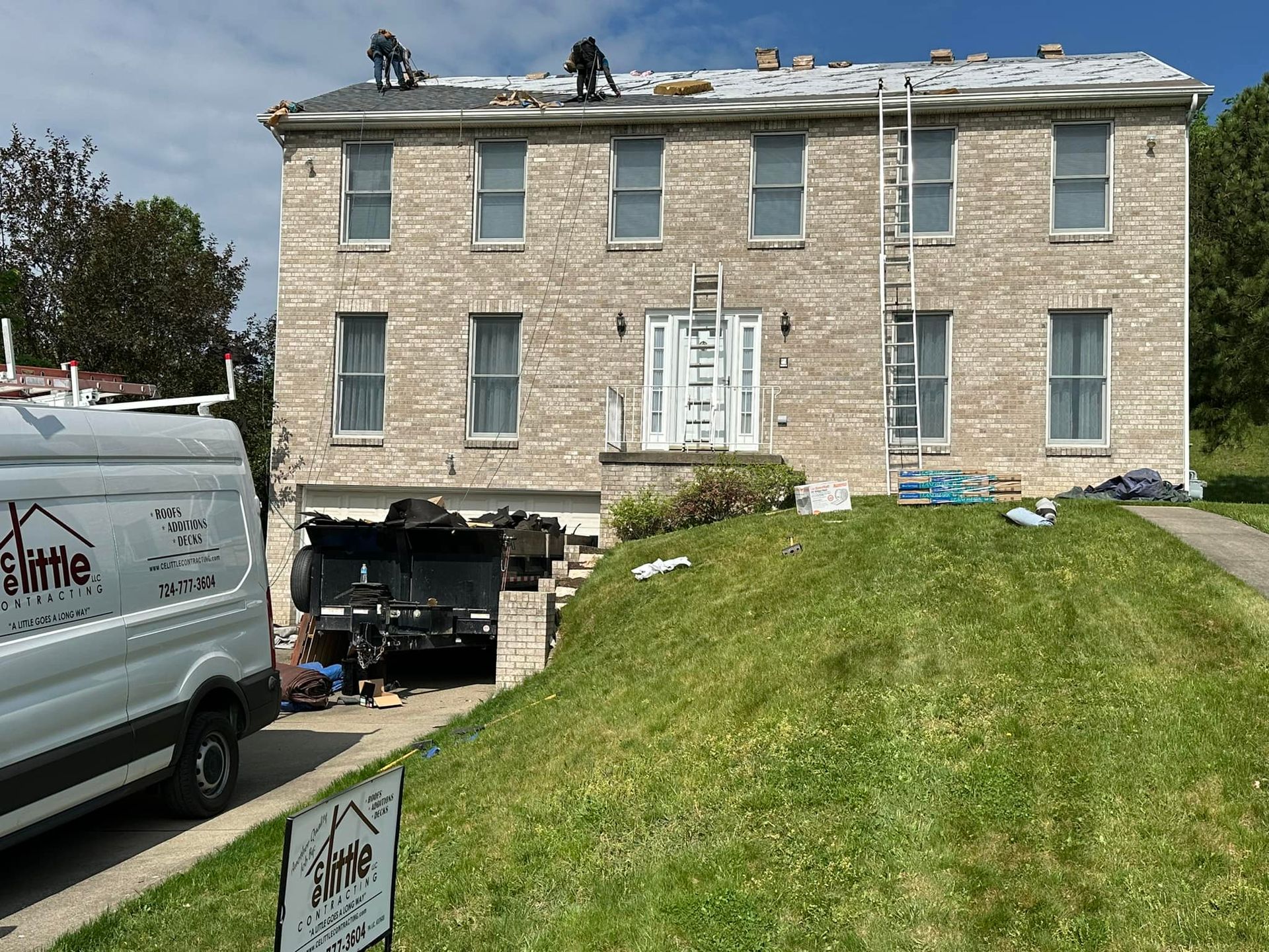 A white van is parked in front of a large brick house.
