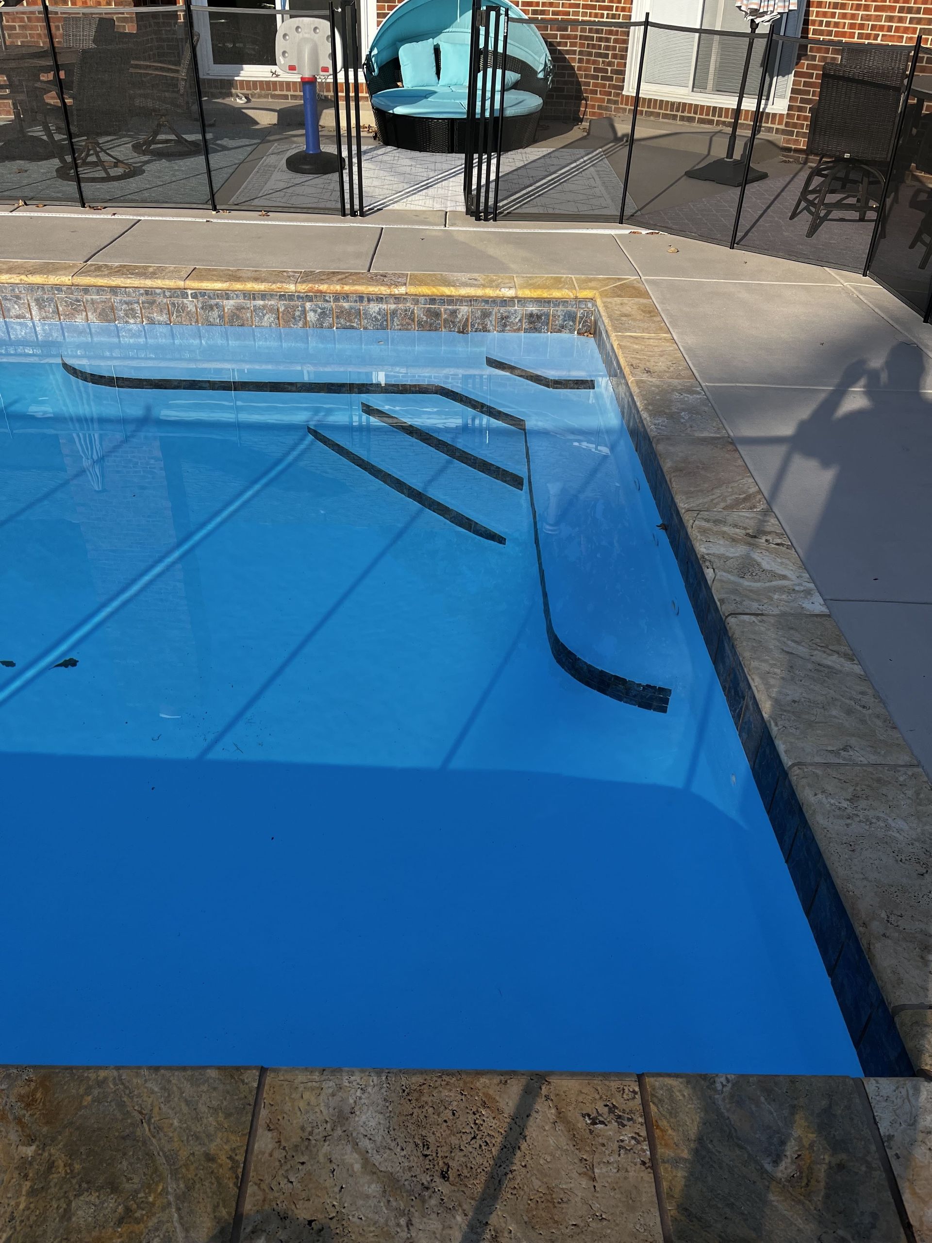Covered swimming pool with a blue tarp and a few pool cleaning tools on top.