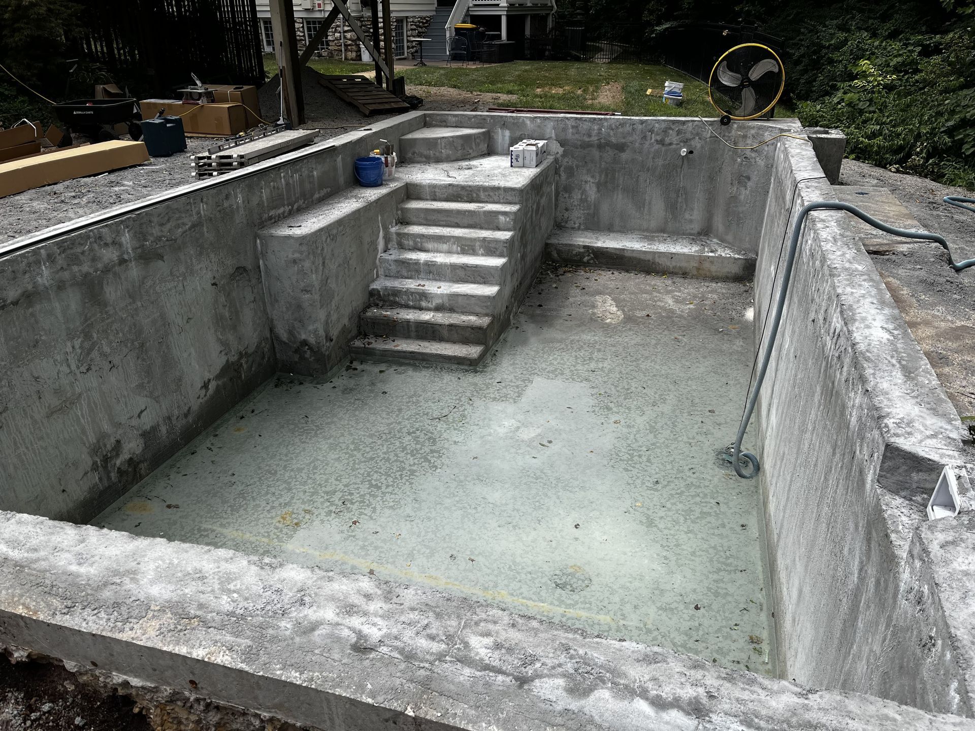 Empty concrete pool under construction with stairs and unfinished walls outdoors
