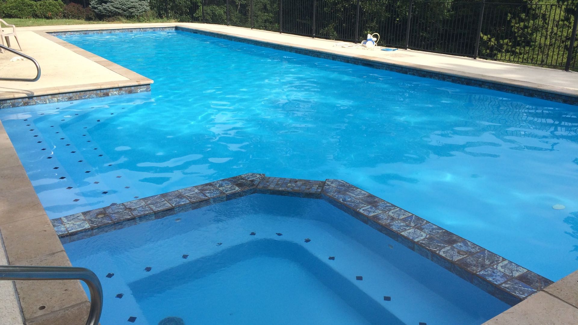 Outdoor swimming pool with bright blue water and a smaller attached spa in the foreground