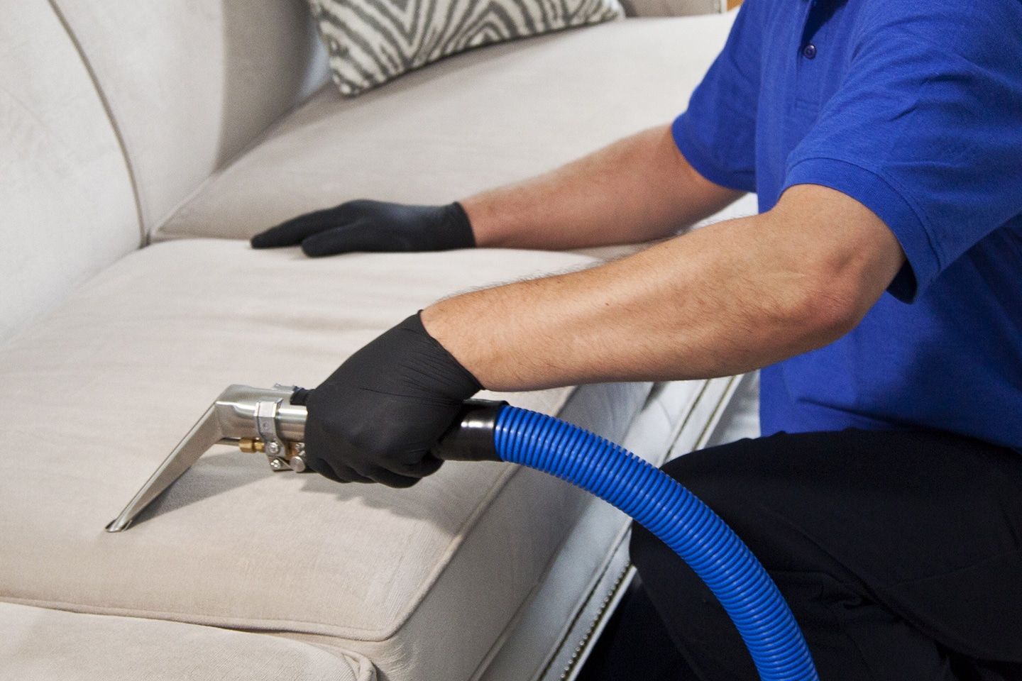Technician cleaning a beige couch with a blue vacuum hose and black gloves Blue Bell, PA
