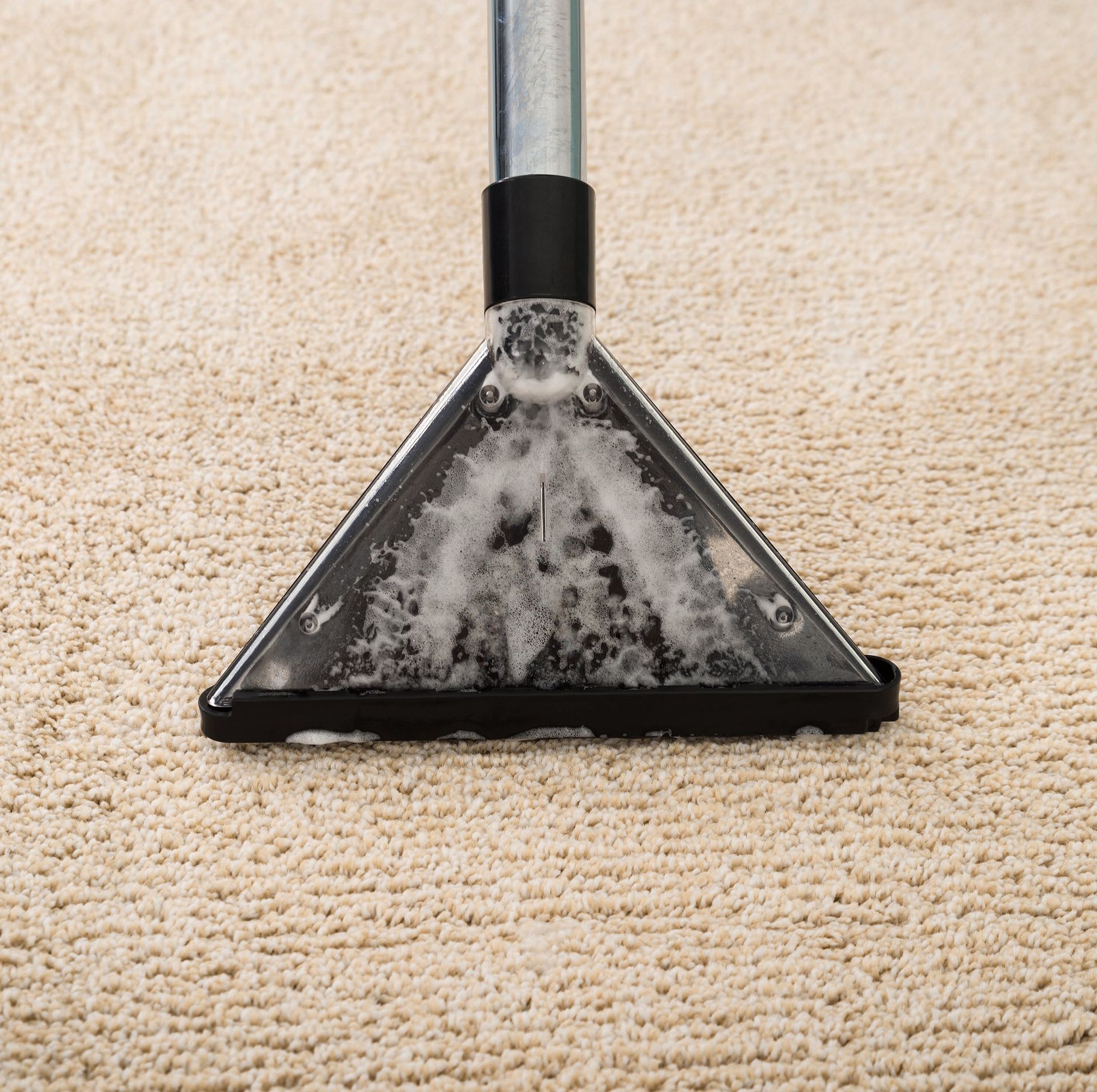 Woman vacuuming a rug in a living room, wearing an apron, smiling.