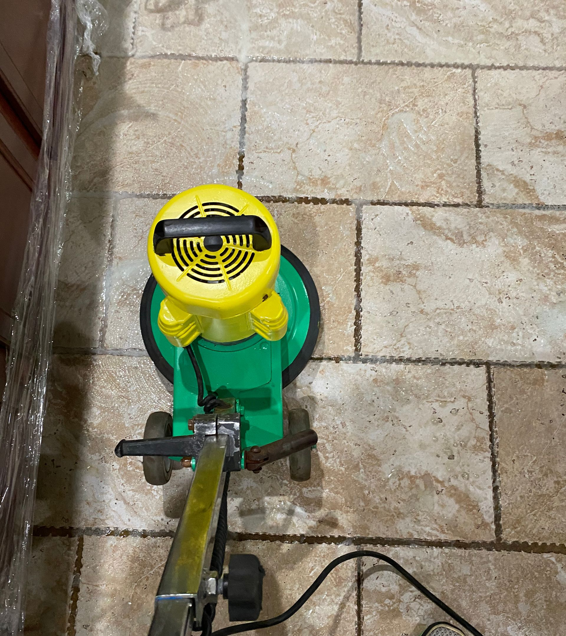 Yellow-and-green walk-behind lawn mower on stone pavement, viewed from above Blue Bell, PA