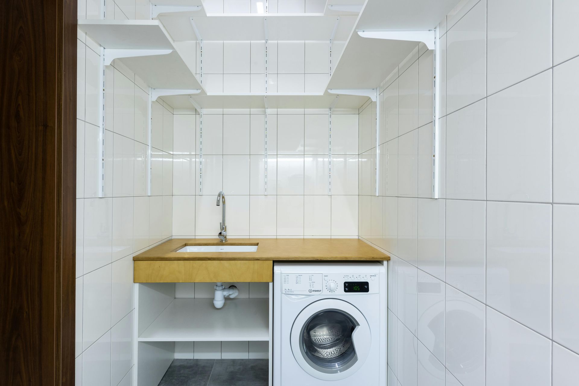 Laundry room with blue walls, white cabinets, and a gray washer and dryer set. A window is in the room.