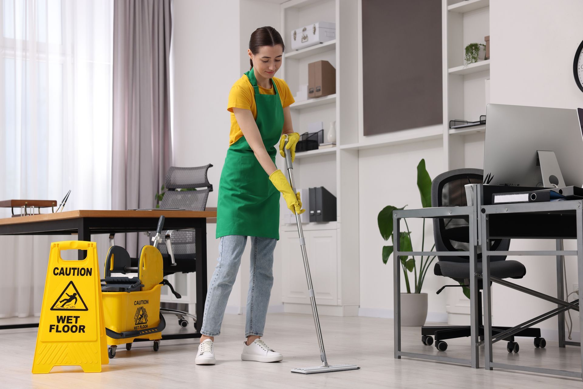 Person installing carpet, using a tool to trim it along a white wall.