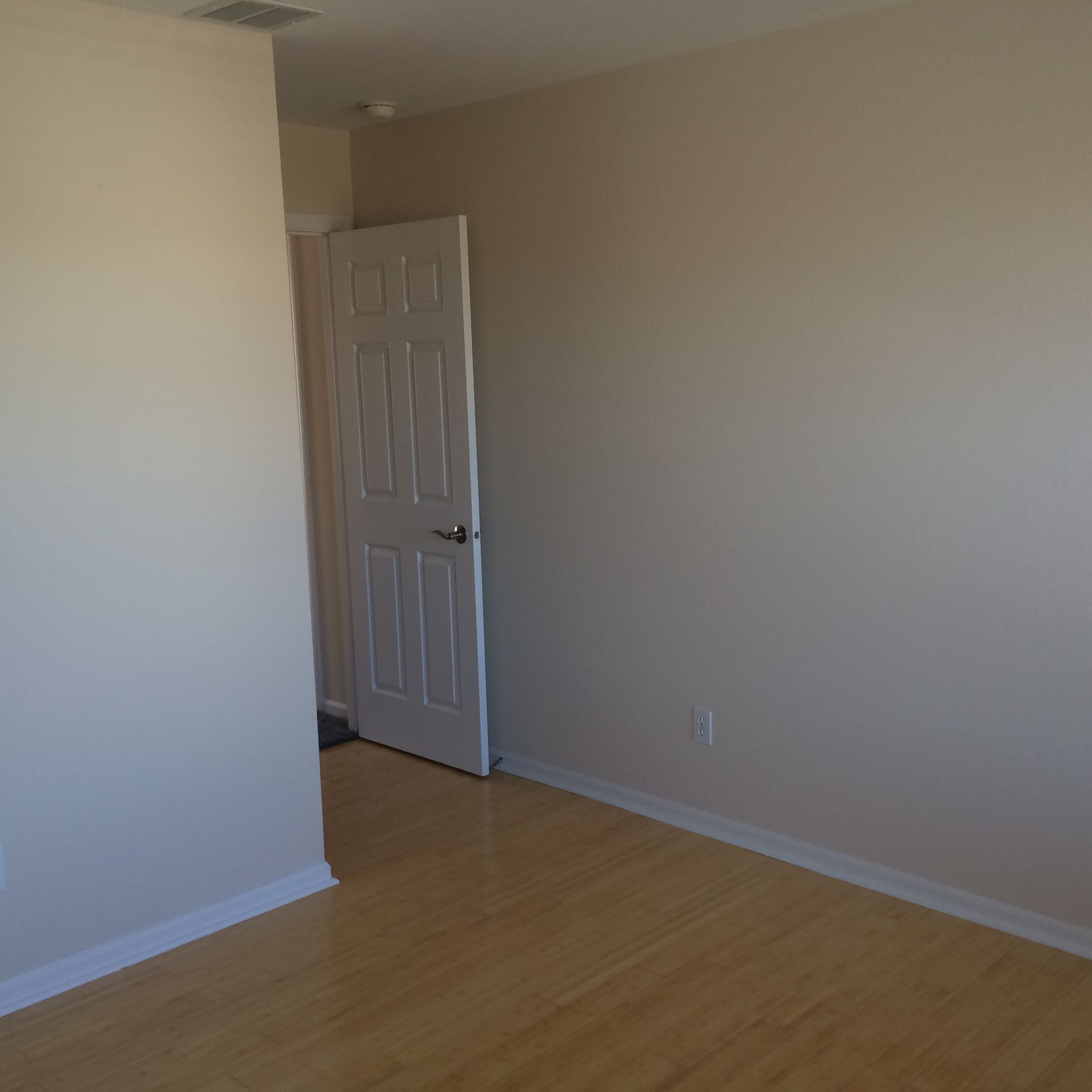 Empty beige room with wood floor and an open white door