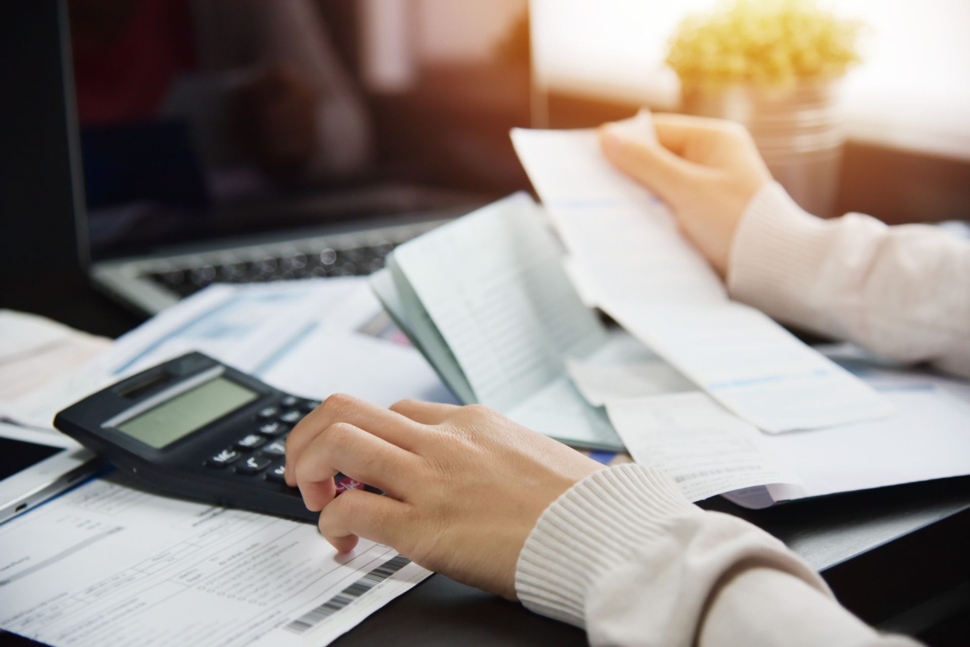 A person is using a calculator while holding a piece of paper.
