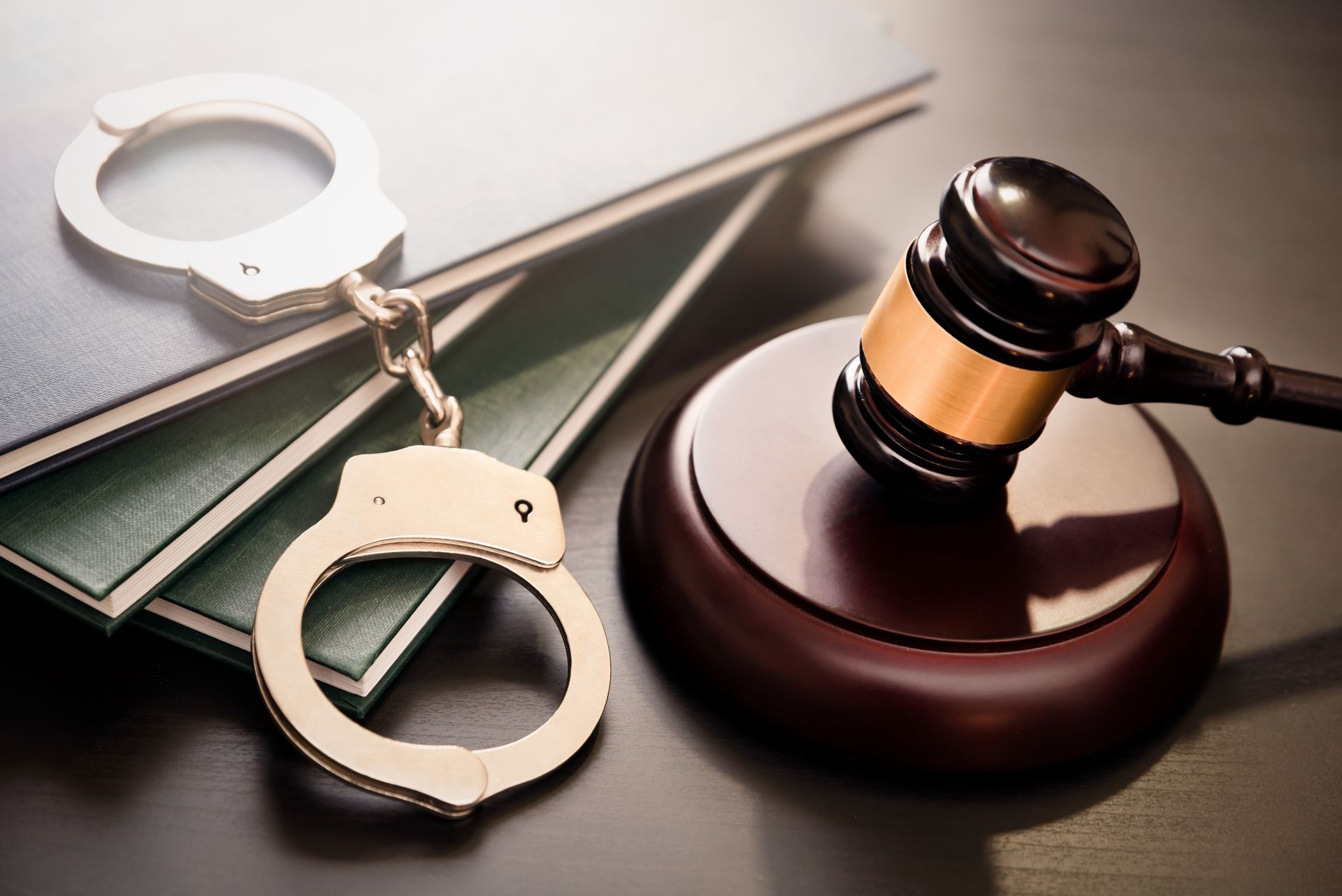 A pair of handcuffs sitting on top of a stack of books next to a judge's gavel.