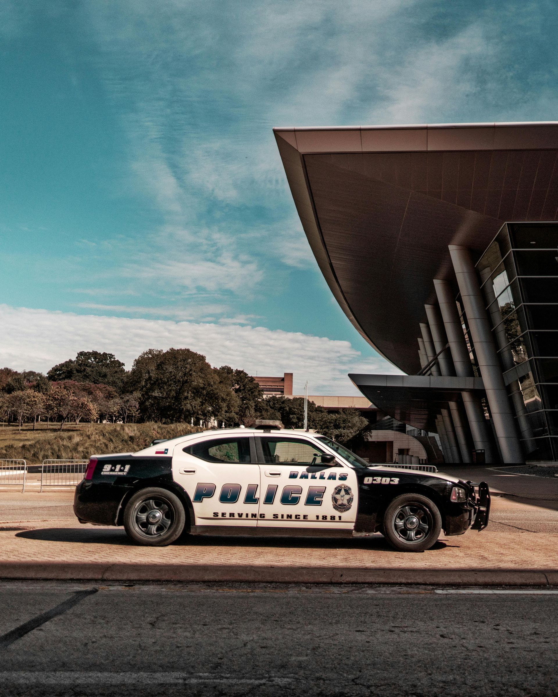 A police car is parked in front of a large building.