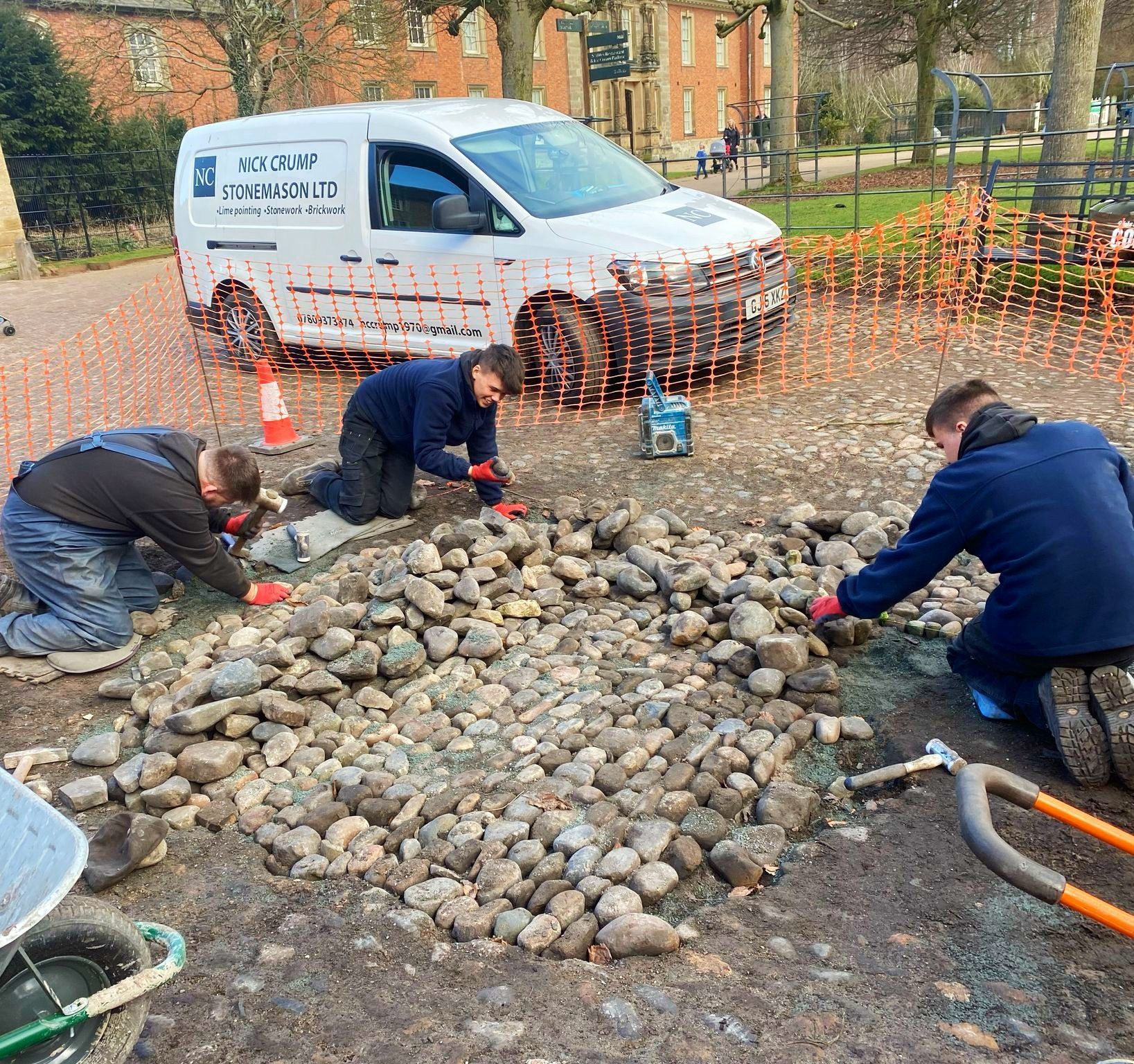 A group of men are working on a cobbled path in front of a white van. cobble repairs