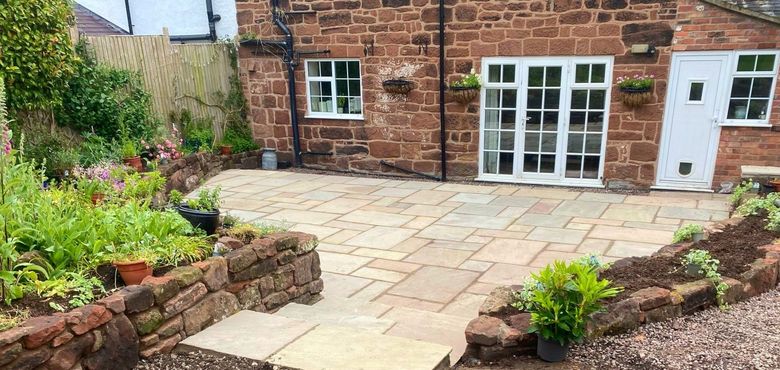 A brick house with a flagstone patio in front of it.