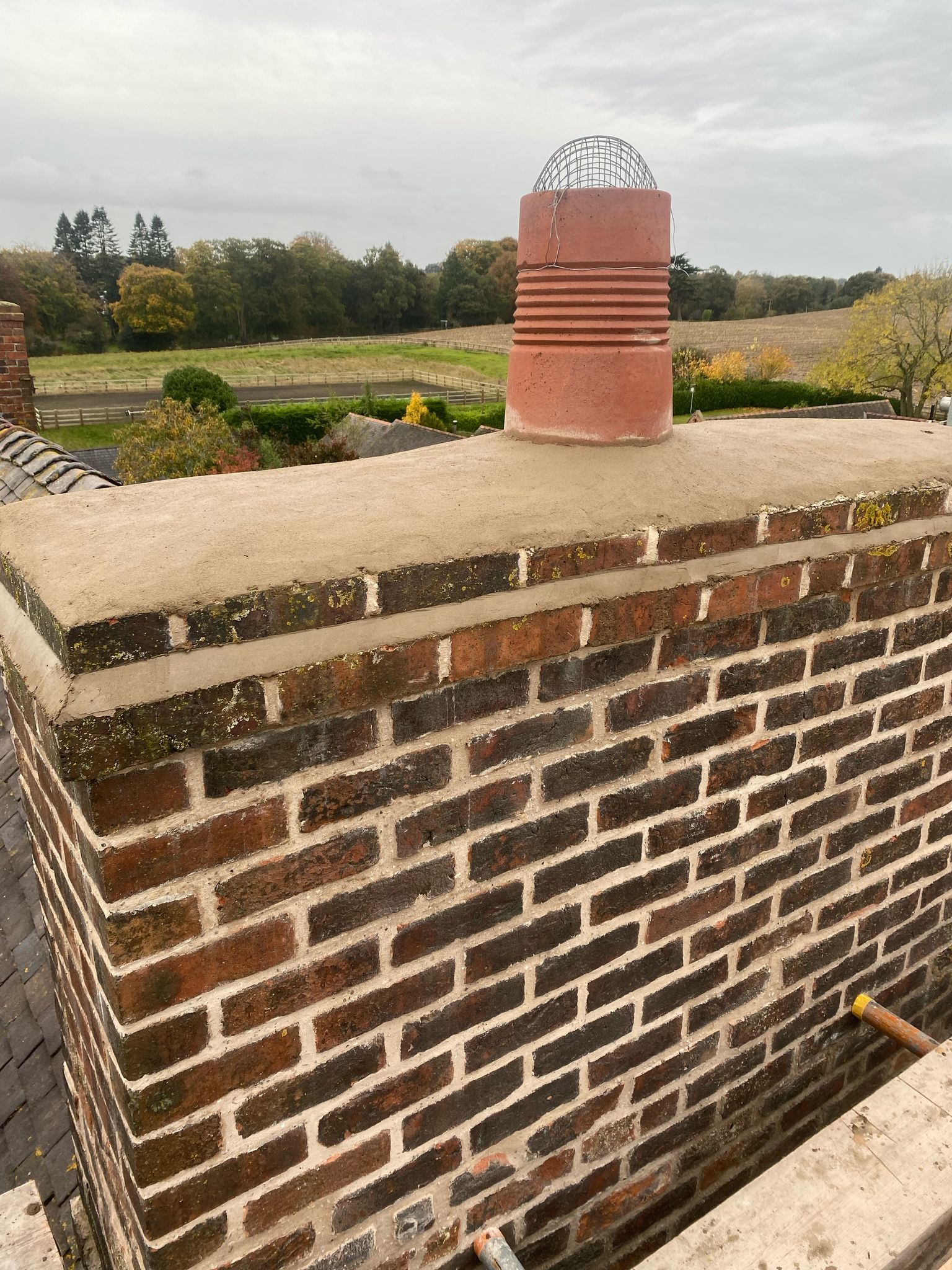 A brick chimney is sitting on top of a brick wall.