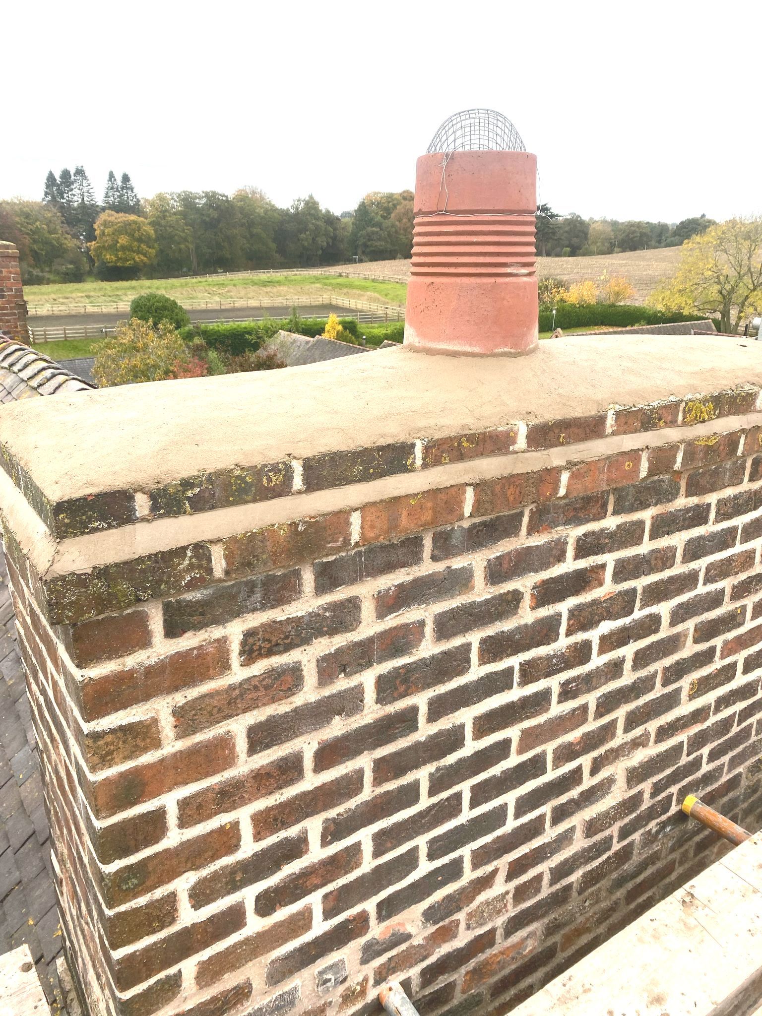 A brick chimney is sitting on top of a brick wall.