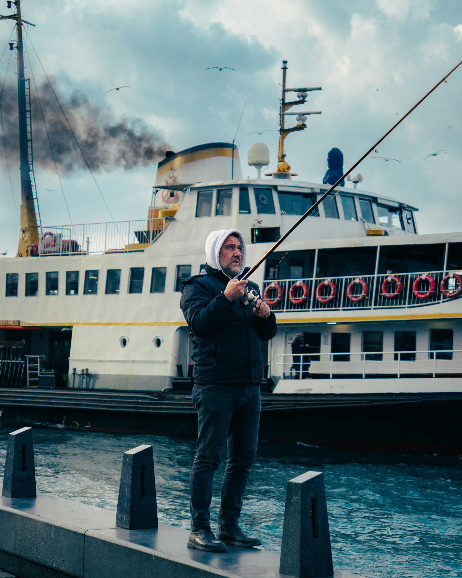 A man is fishing in front of a boat in the water.