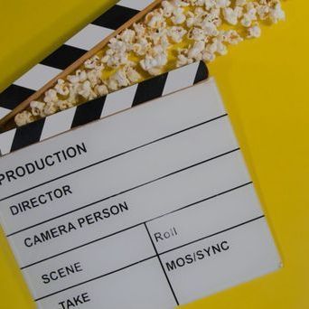 Clapperboard with popcorn on a yellow background, ready for filming.