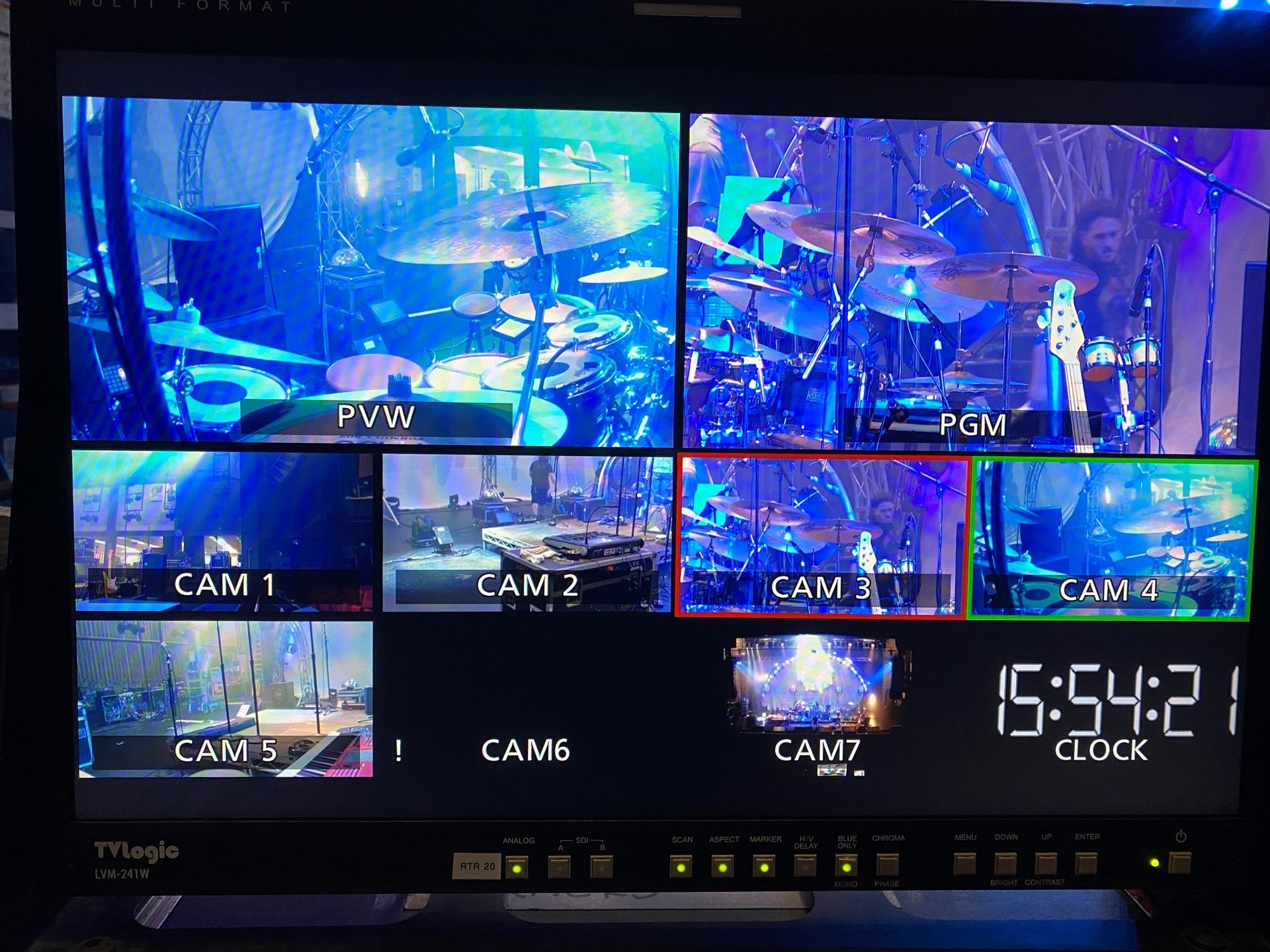 Multi-view display showing seven camera feeds of a live music performance, including drummer, stage, and timecode.