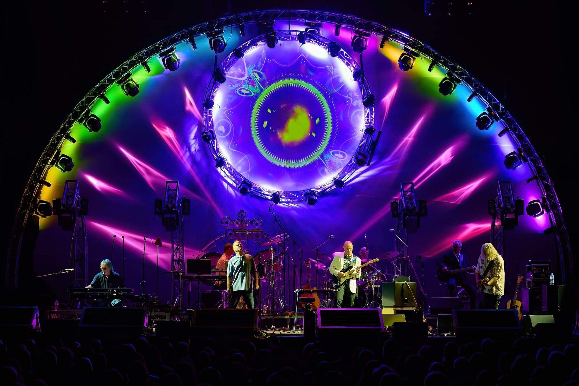 Band performing on stage with colorful light display.