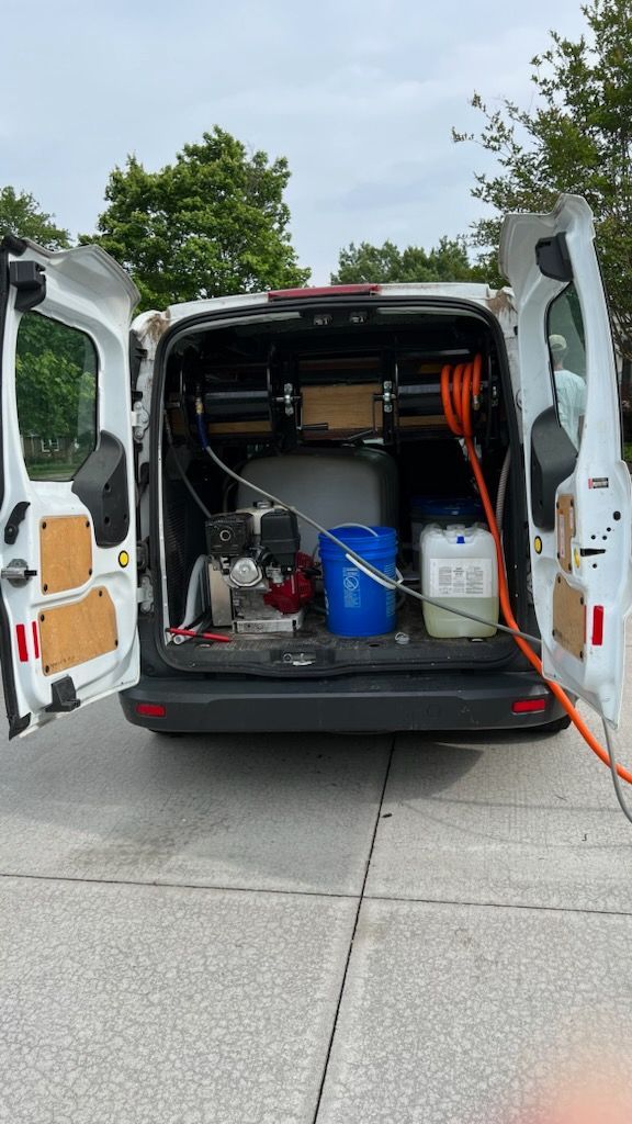 Open white van with rear doors open, showing tools, cables, blue bucket, and equipment inside.