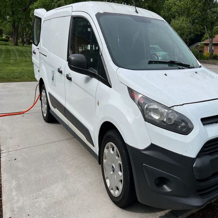 White cargo van parked on a driveway with an orange hose connected at the rear