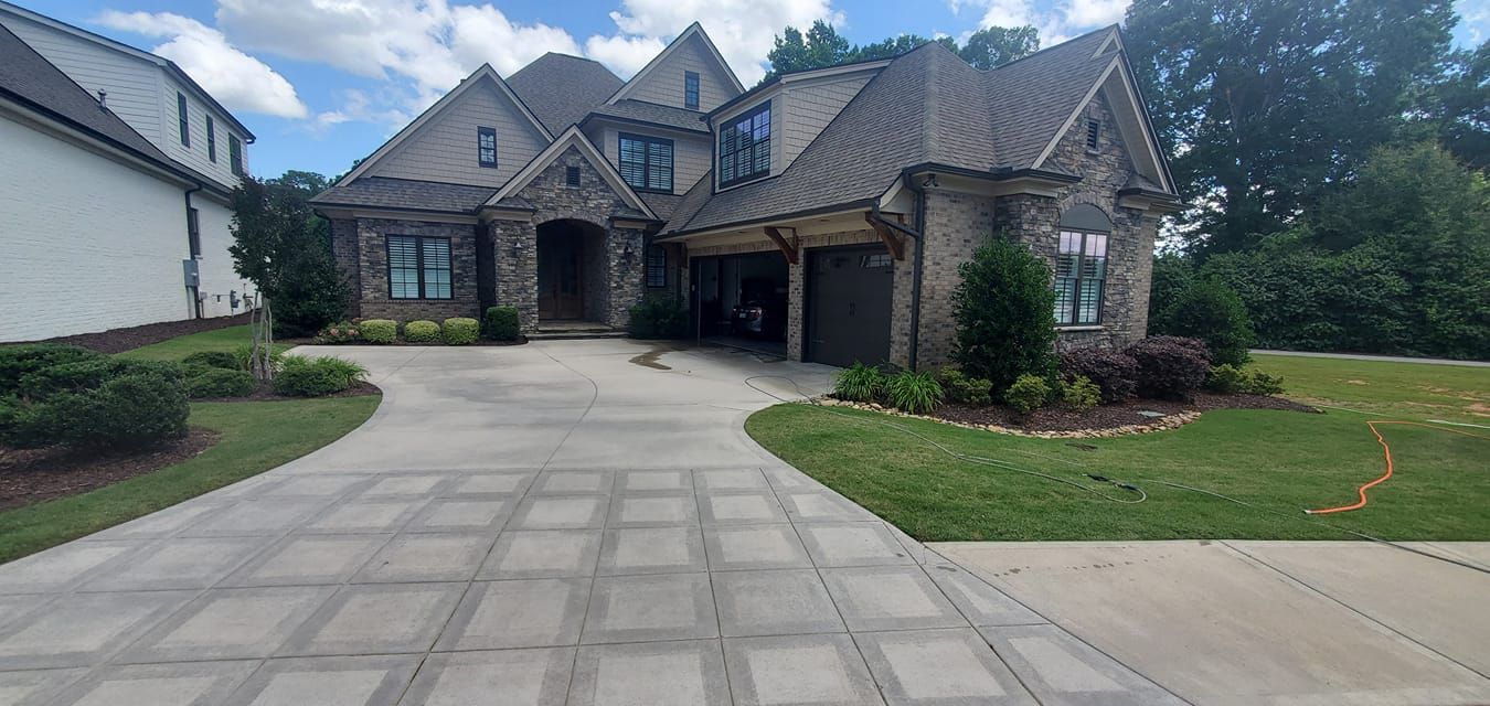 Large stone house with a wide driveway, green lawn, and an attached garage
