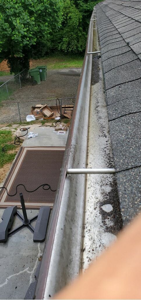 Rooftop view of a narrow side yard with a ladder, white gutter, and brick patio below.