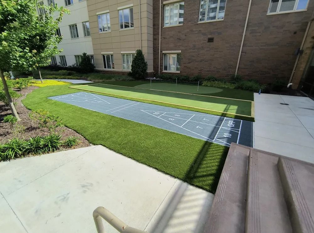 Accessible stone path across a green courtyard beside a building, with patios and garden beds.