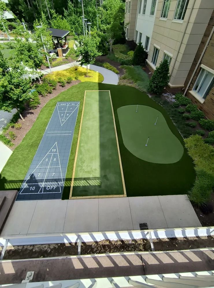 Backyard bocce court with chalk scoring lines beside a green putting green and patio