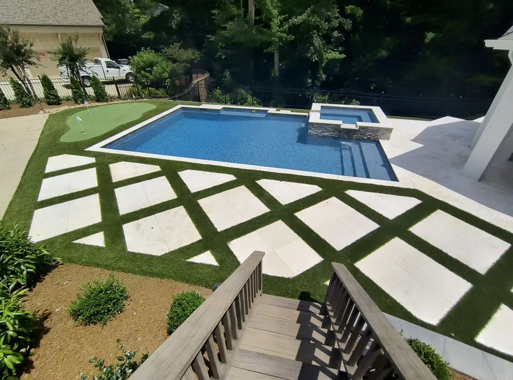 Backyard pool with geometric white stone walkway and stairs leading down from a deck
