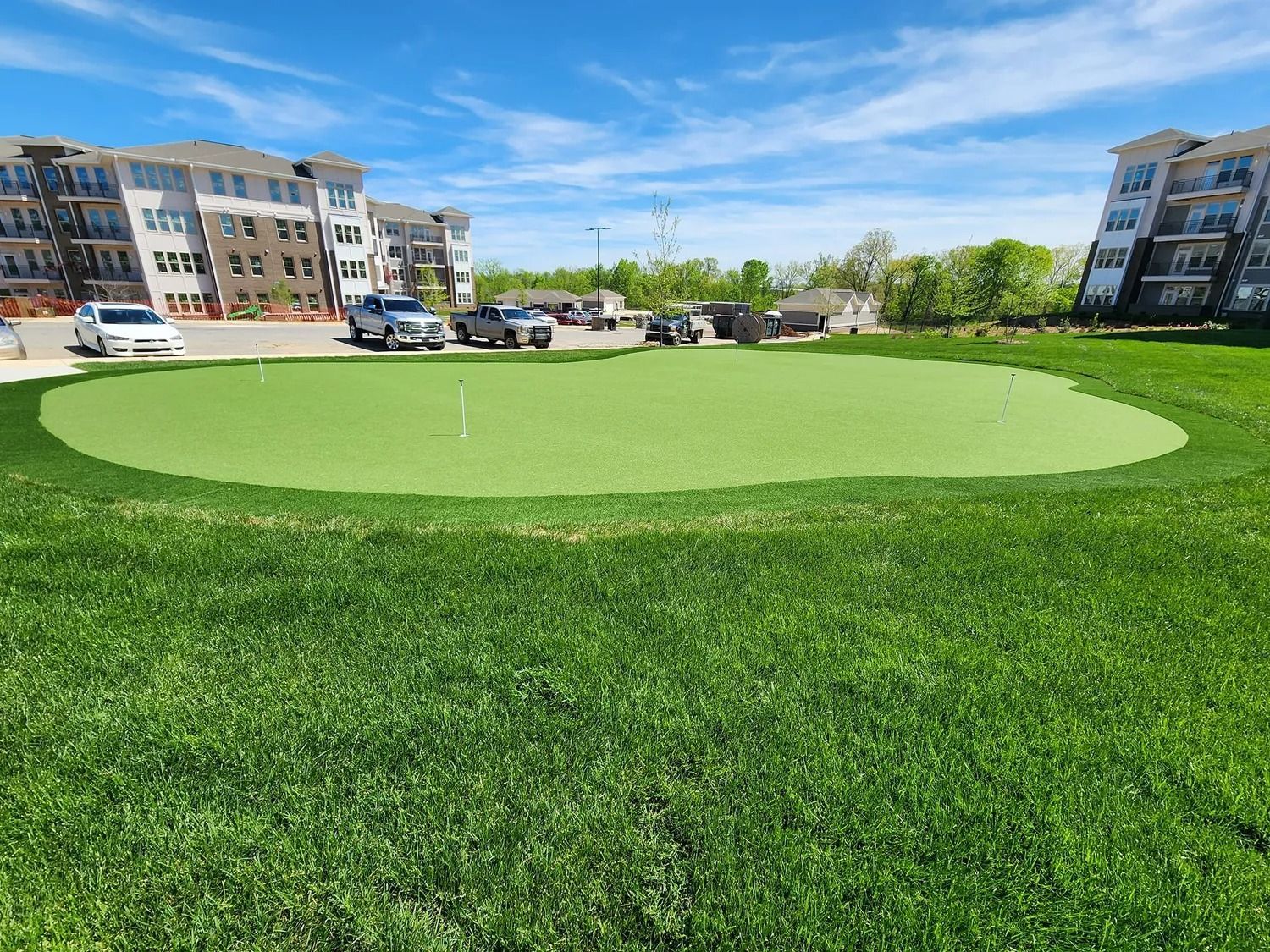 Green lawn in a residential courtyard between apartment buildings under a clear sky