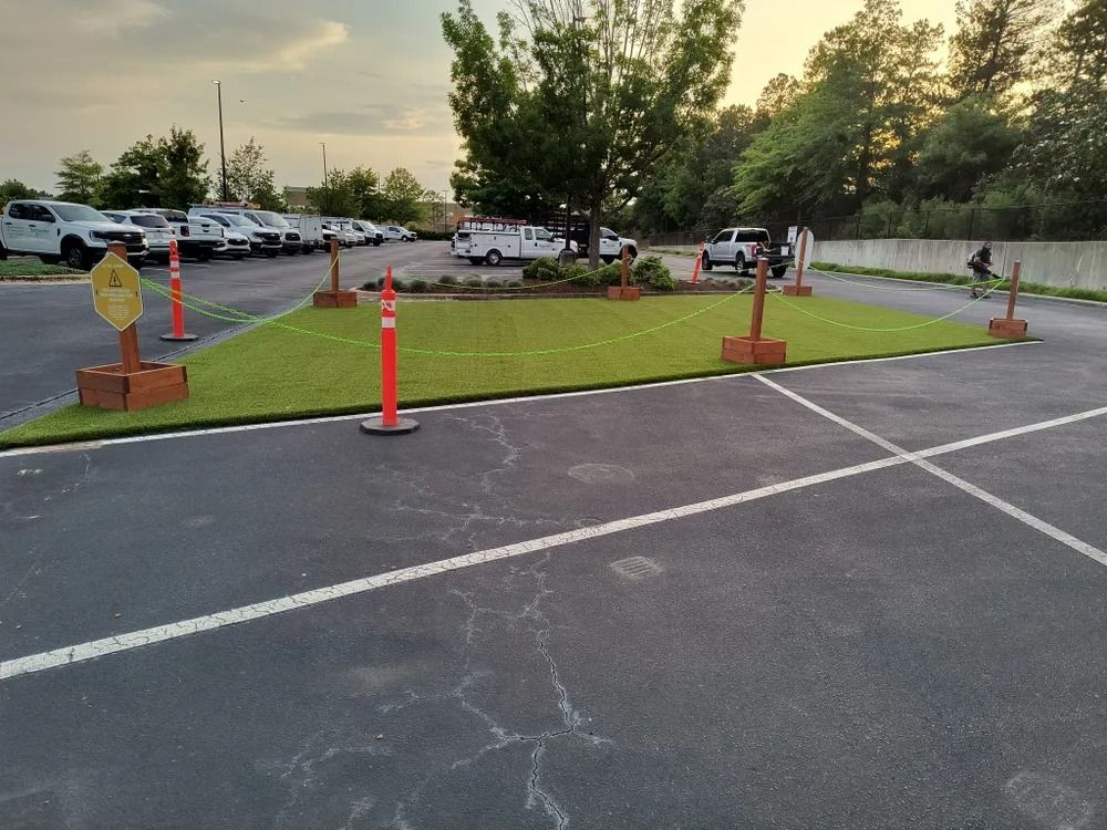 Parking lot entrance with orange cones and barriers around a small grassy area at dusk