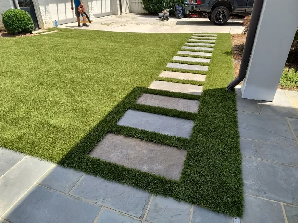 Landscaped yard with a diagonal stepping-stone path through green grass beside a paved patio