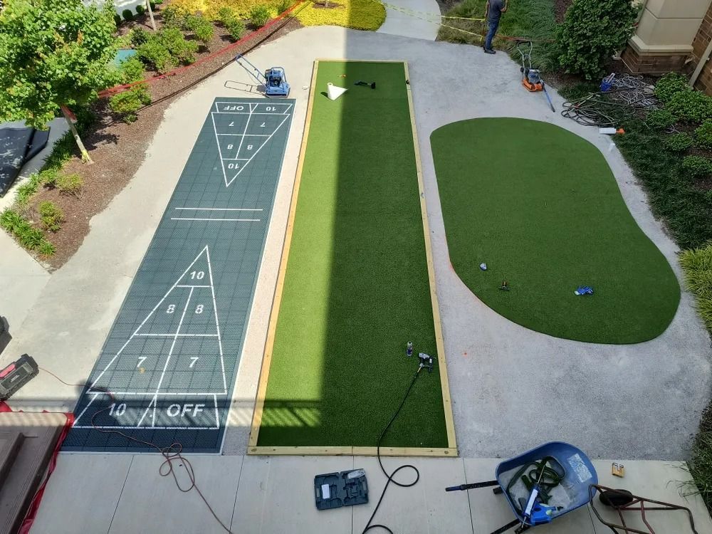 Aerial view of a bocce court and adjacent green lawn in a landscaped backyard