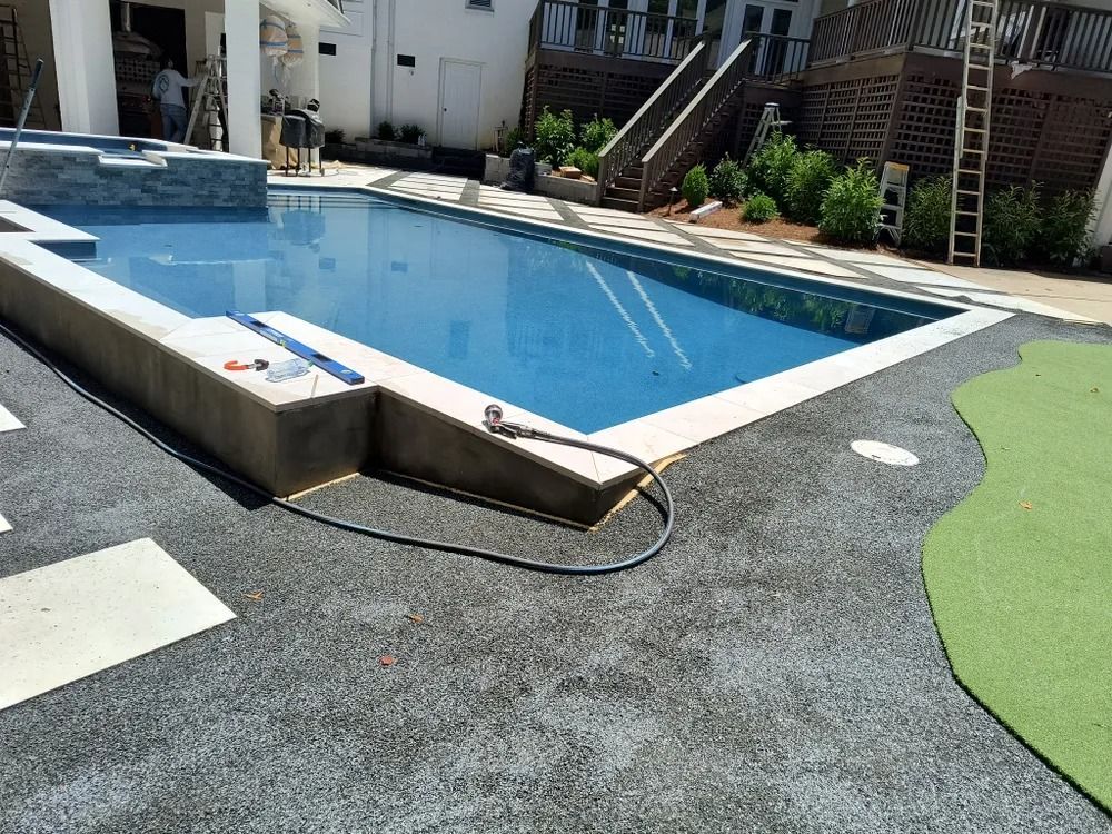 Outdoor swimming pool with a blue surface, gray deck, and green turf around it