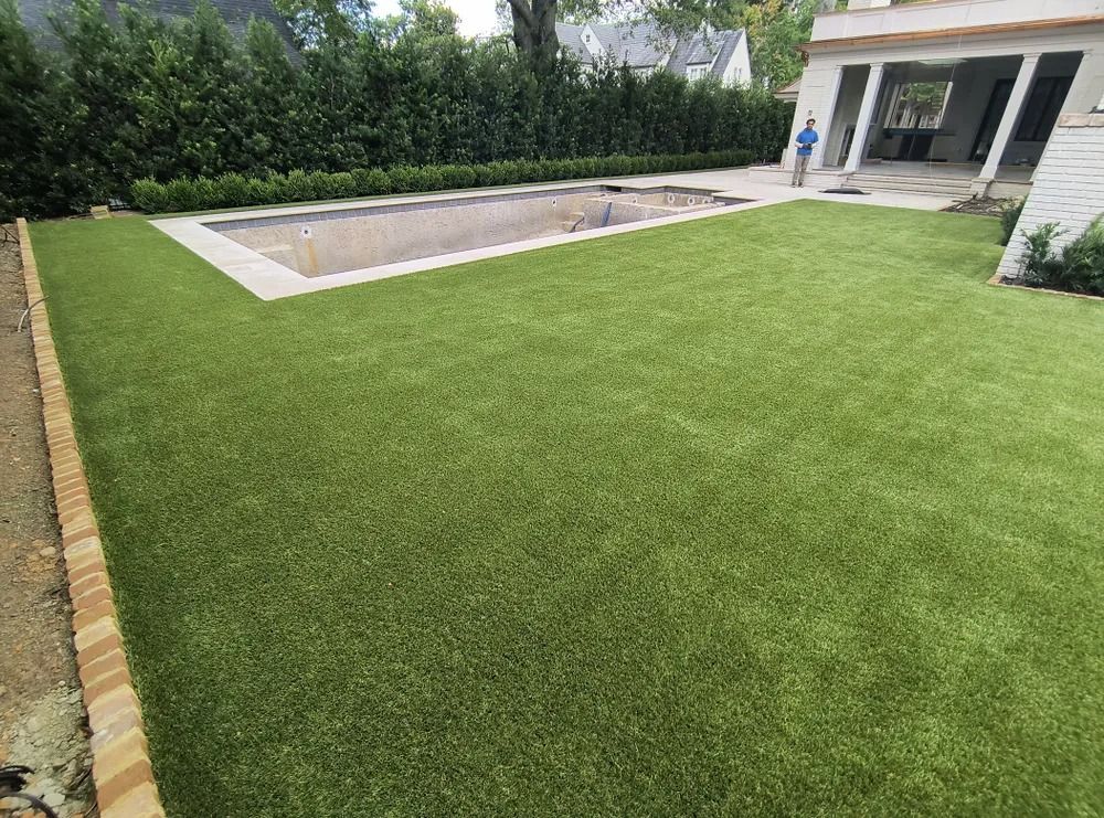Backyard with a green lawn and rectangular in-ground pool beside a patio and house.