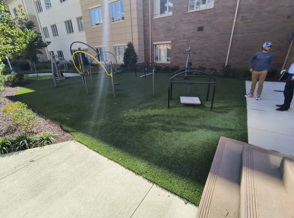 Apartment courtyard with playground equipment, a bench, and two people on a walkway.