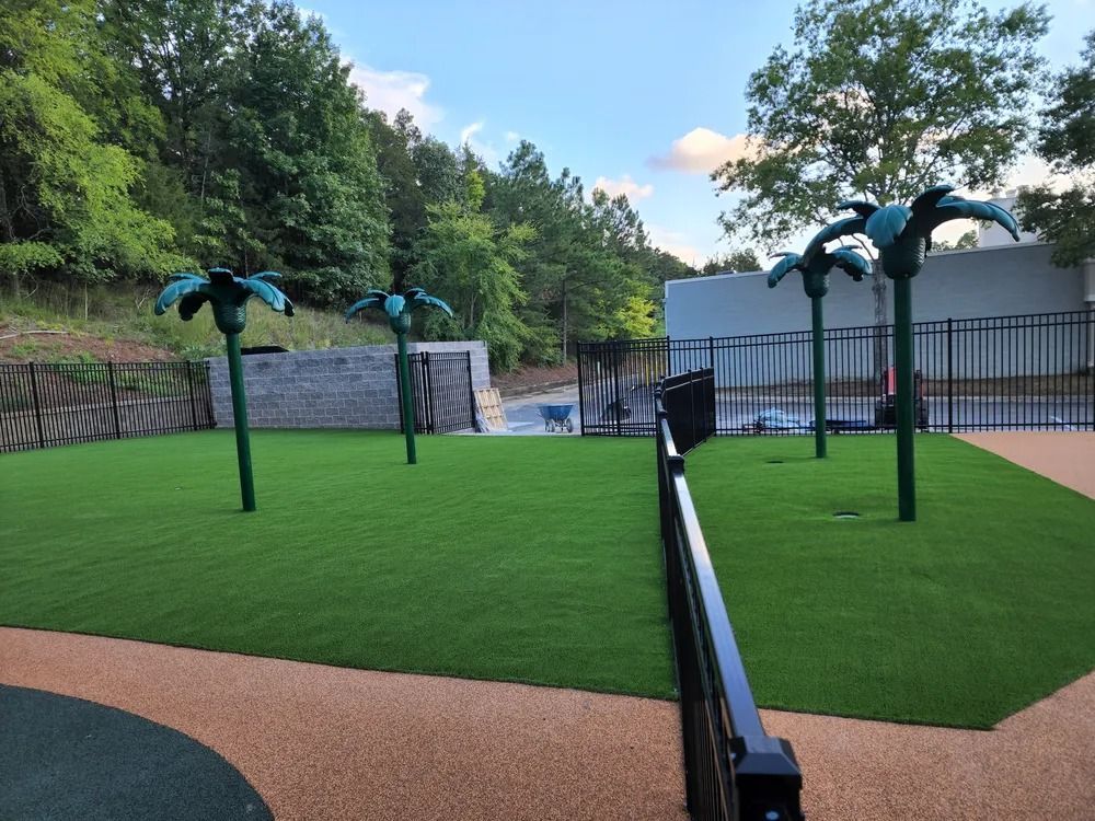 Outdoor mini-golf course with bright green turf, black rails, and palm-shaped obstacles near trees and a building