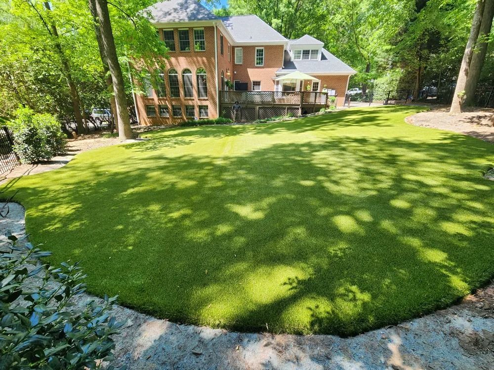 Brick house with a large green lawn and trees in a wooded yard