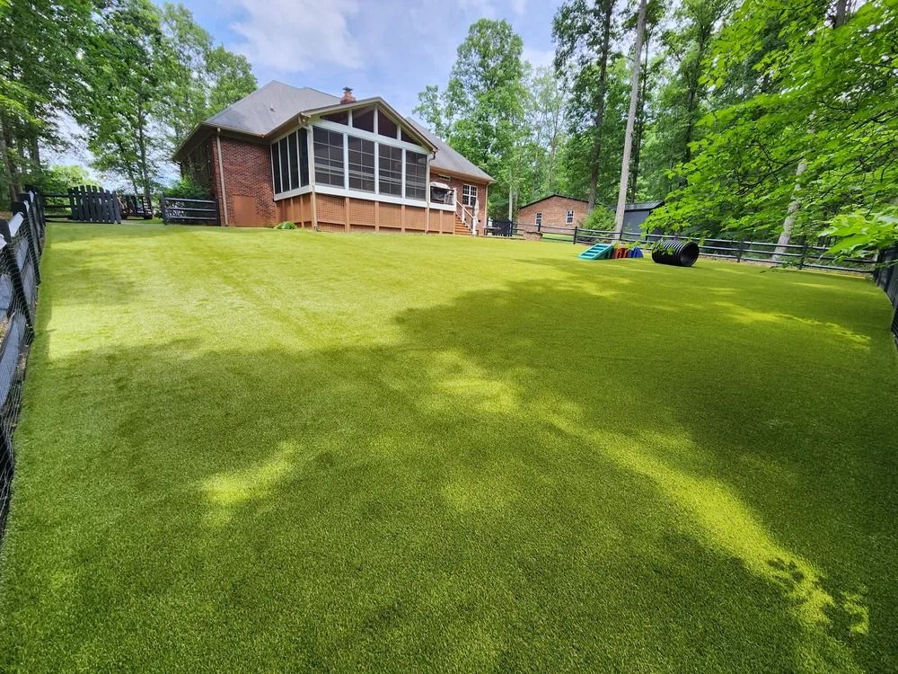 Large brick house with a sunroom overlooking a wide green lawn and trees