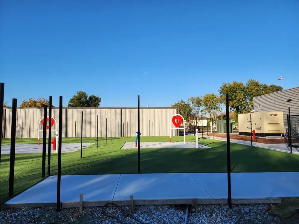Outdoor basketball court with black poles, white surface, and red hoops under a clear blue sky