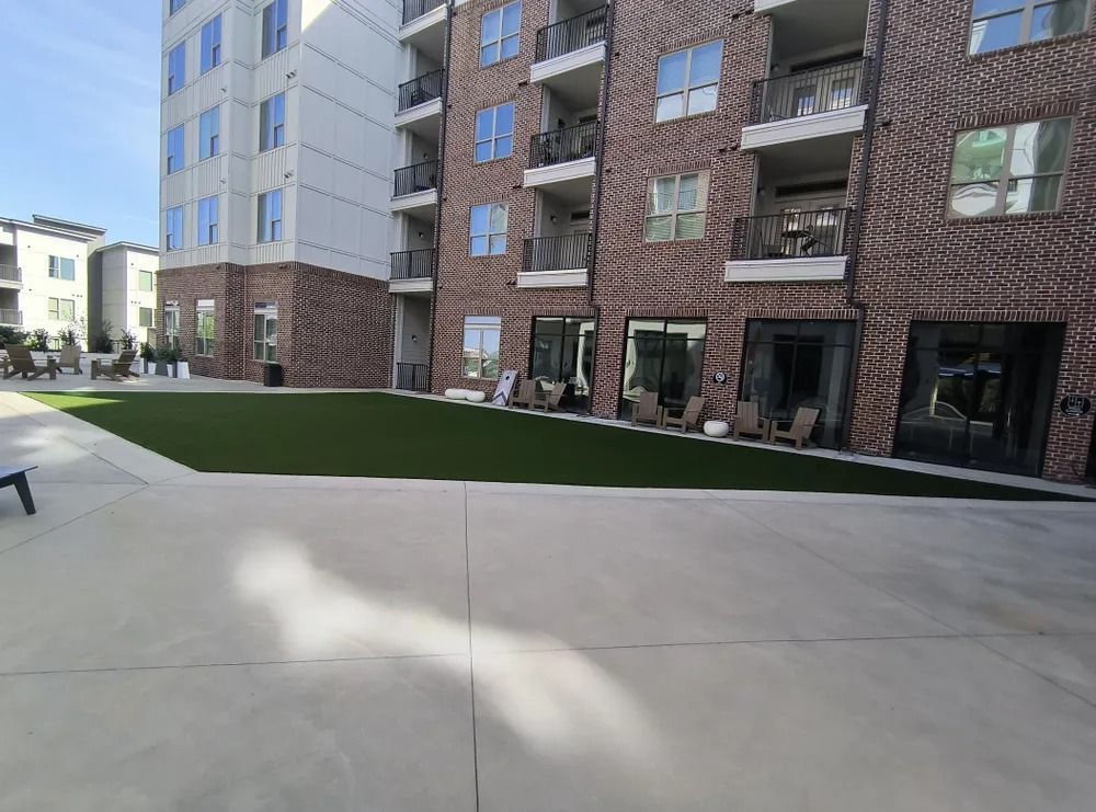 Modern apartment courtyard with concrete walkway, artificial grass, and brick and glass buildings