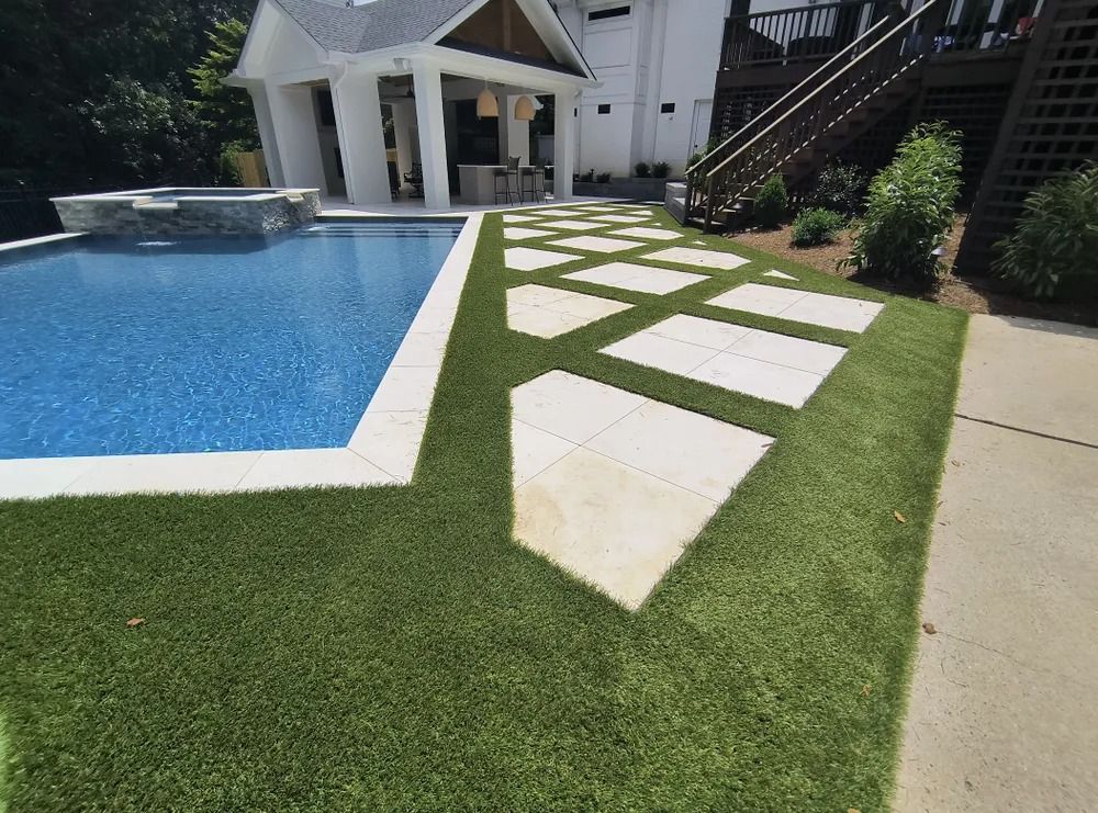 Modern backyard pool with geometric white stepping stones in green grass beside a patio