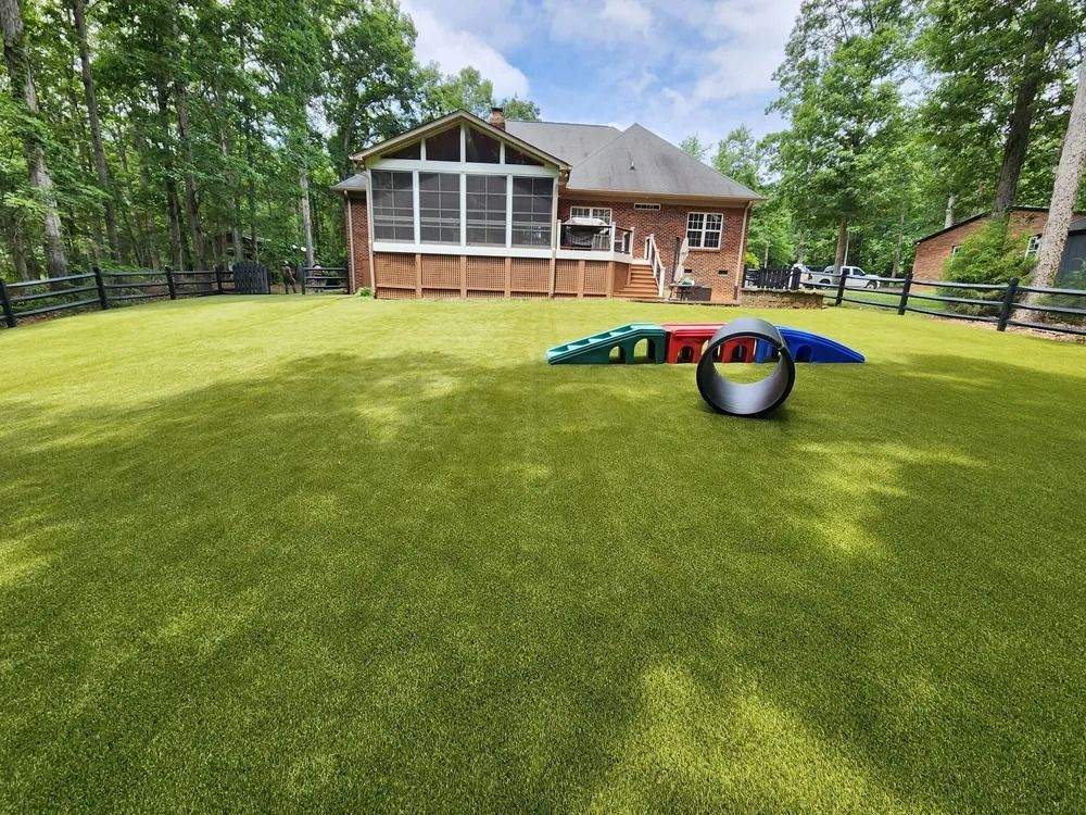 Wooded backyard with a house, sloped lawn, and colorful agility tunnel toys