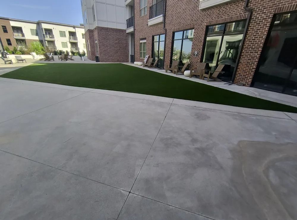 Courtyard walkway beside brick apartment buildings and green lawn under clear daylight