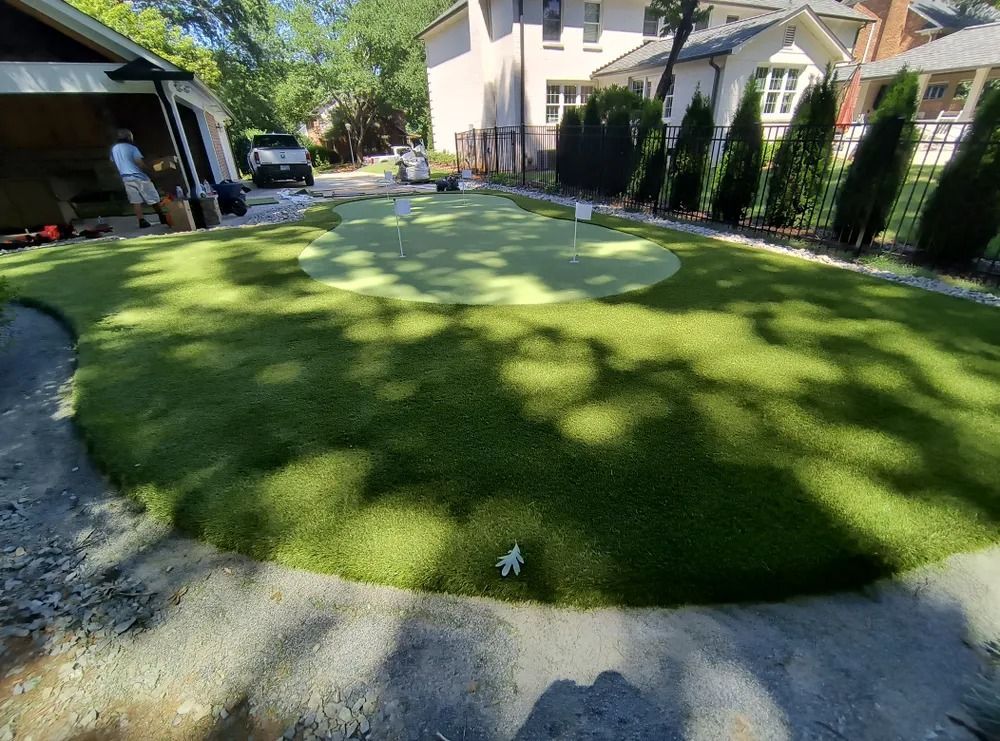 Backyard lawn with circular patchy grass, driveway on left, and houses in the background.