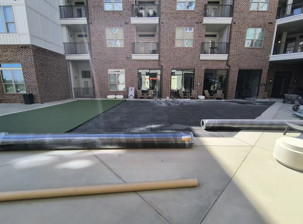 Apartment courtyard with rooftop seating area, black mats, and a wooden dowel on the ground.