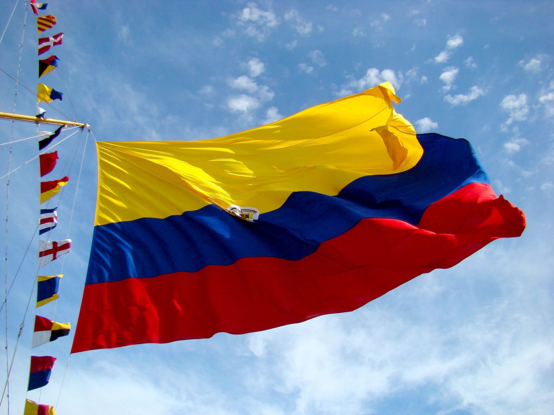 Colombian flag waving against a blue sky with clouds